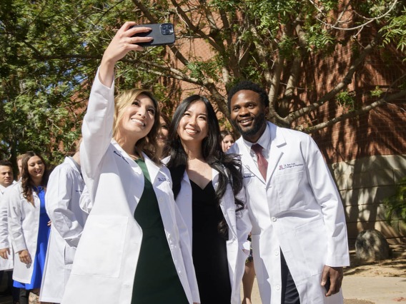 (From left) Brooke Nguyen, Ngoc Nguyen and Anyangatia Ndobegang capture the moment as they leave Centennial Hall after the R. Ken Coit College of Pharmacy class of 2023 white coat ceremony. 