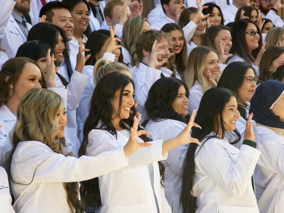 The class of 2023 R. Ken Coit College of Pharmacy students give the Wildcat sign during their class photo after their white coat ceremony at Centennial Hall.