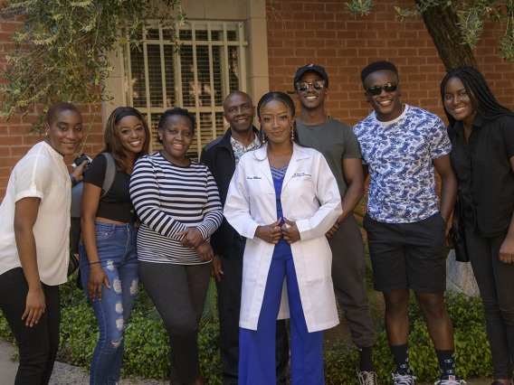 Judy Mburu pauses for a photo with family and friends after receiving her white coat during the R. Ken Coit College of Pharmacy class of 2023 white coat ceremony.