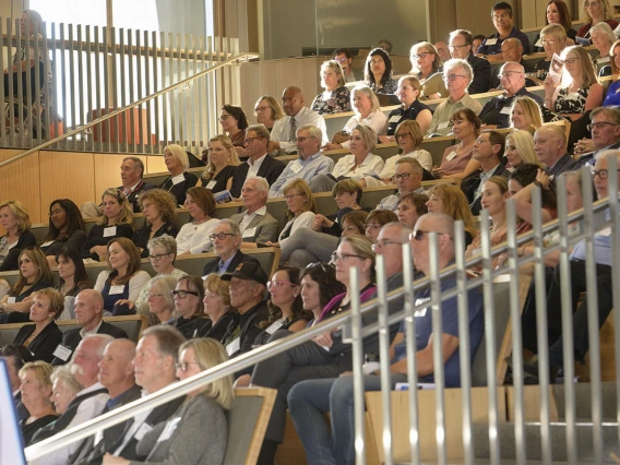 Hundreds of people sit in stadium-style seats during a memorial service for Mel Zuckerman.