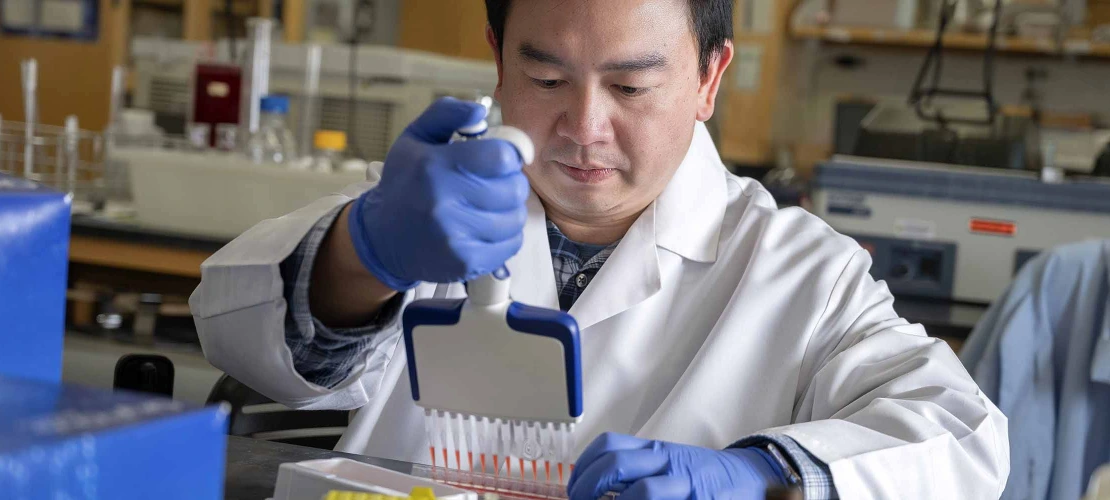 researcher in a white lab coat holding a multichannel pipette