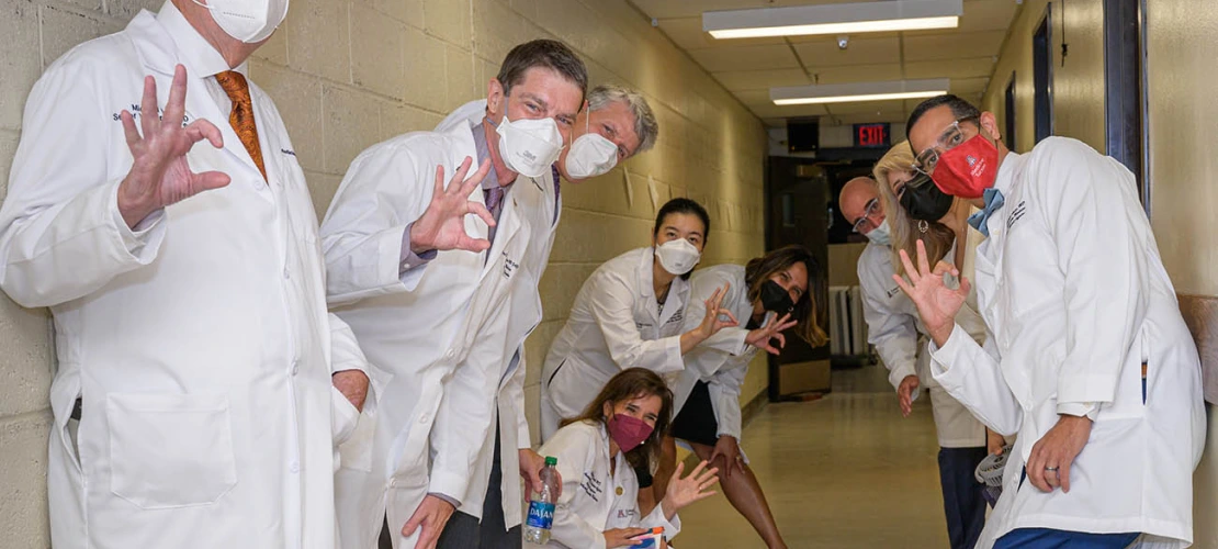 Michael D. Dake, MD, senior vice president for the University of Arizona Health Sciences (left) and UArizona College of Medicine – Tucson faculty members flash the Wildcat sign as they wait to go on stage at Centennial Hall for the Class of 2026 white coat ceremony.