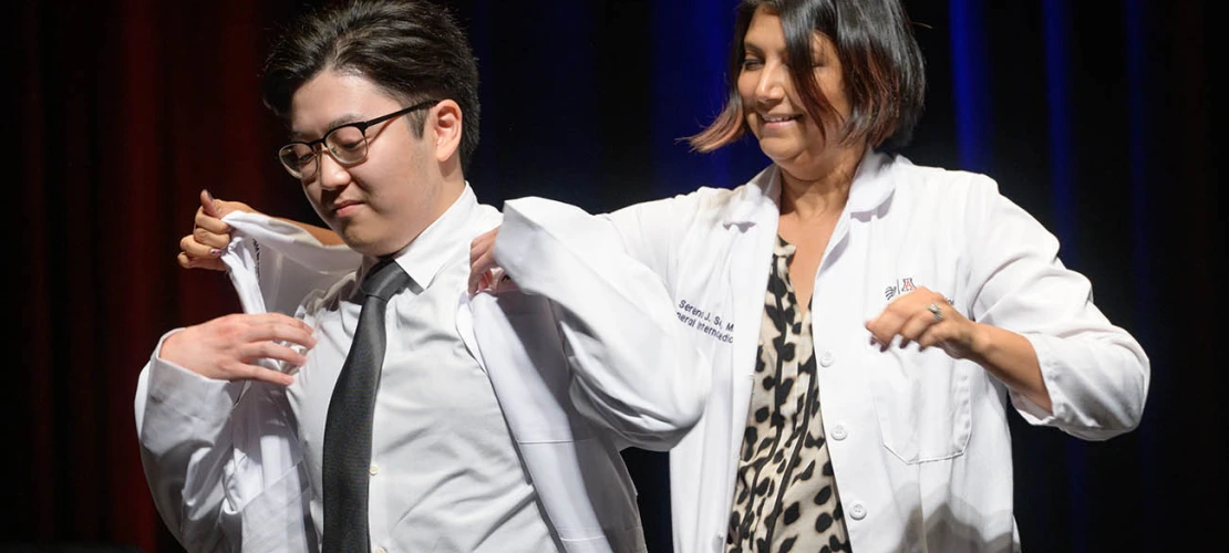 Andrew Endo is given his white coat by Serena Scott, MD, assistant professor of medicine, at the UArizona College of Medicine – Tucson Class of 2026 white coat ceremony.