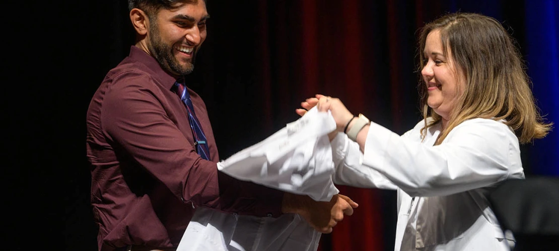 Rorie Robinson prepares to be coated by clinical assistant professor Joy Bulger Beck, MD, at the UArizona College of Medicine – Tucson Class of 2026 white coat ceremony.