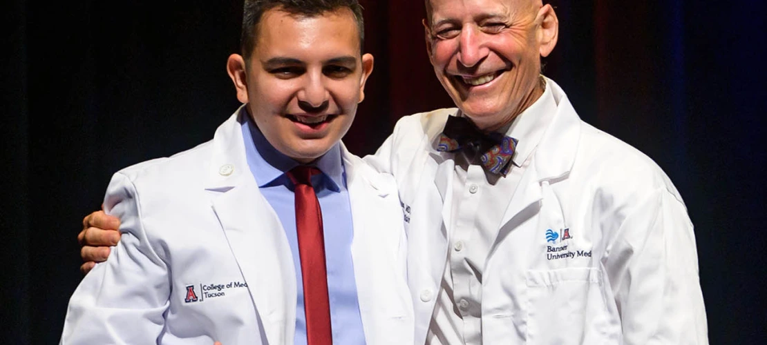 Adrian Franco pauses for a photo with professor Paul Gordon, MD, MPH, after receiving his white coat at the UArizona College of Medicine – Tucson Class of 2026 white coat ceremony.