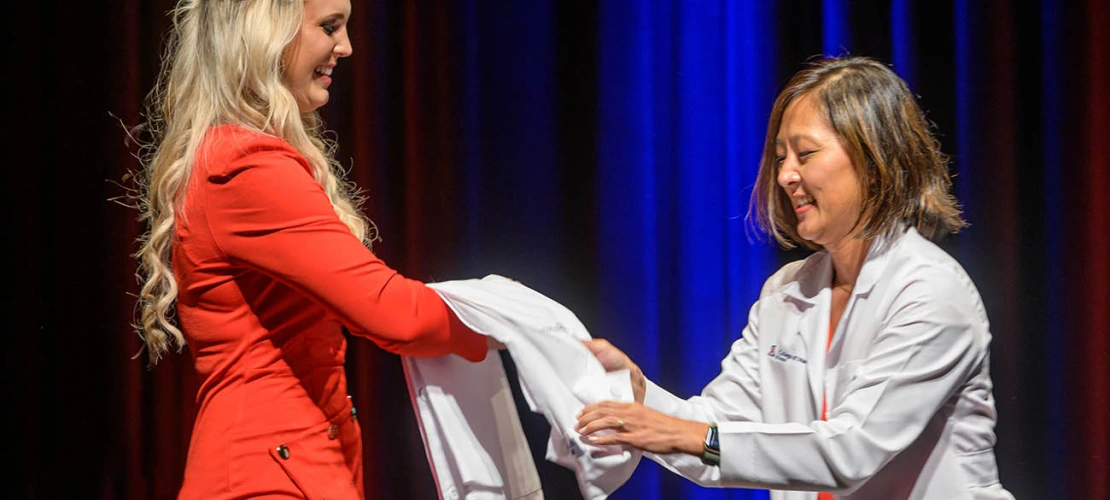 Hailey Patterson prepares to be coated by Alice Min, MD, FACEP, associate dean for career development, at the UArizona College of Medicine – Tucson Class of 2026 white coat ceremony.