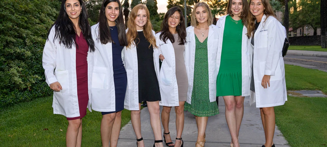 (From left) Sahar Davoudi, Lily Younan, Madisyn Kaus-Peru, Shannon Yee, Marisa Cannon, Sabine Obagi and Katharine Johnson pause for a photo on their way out of Centennial Hall after the College of Medicine – Tucson Class of 2026 white coat ceremony.