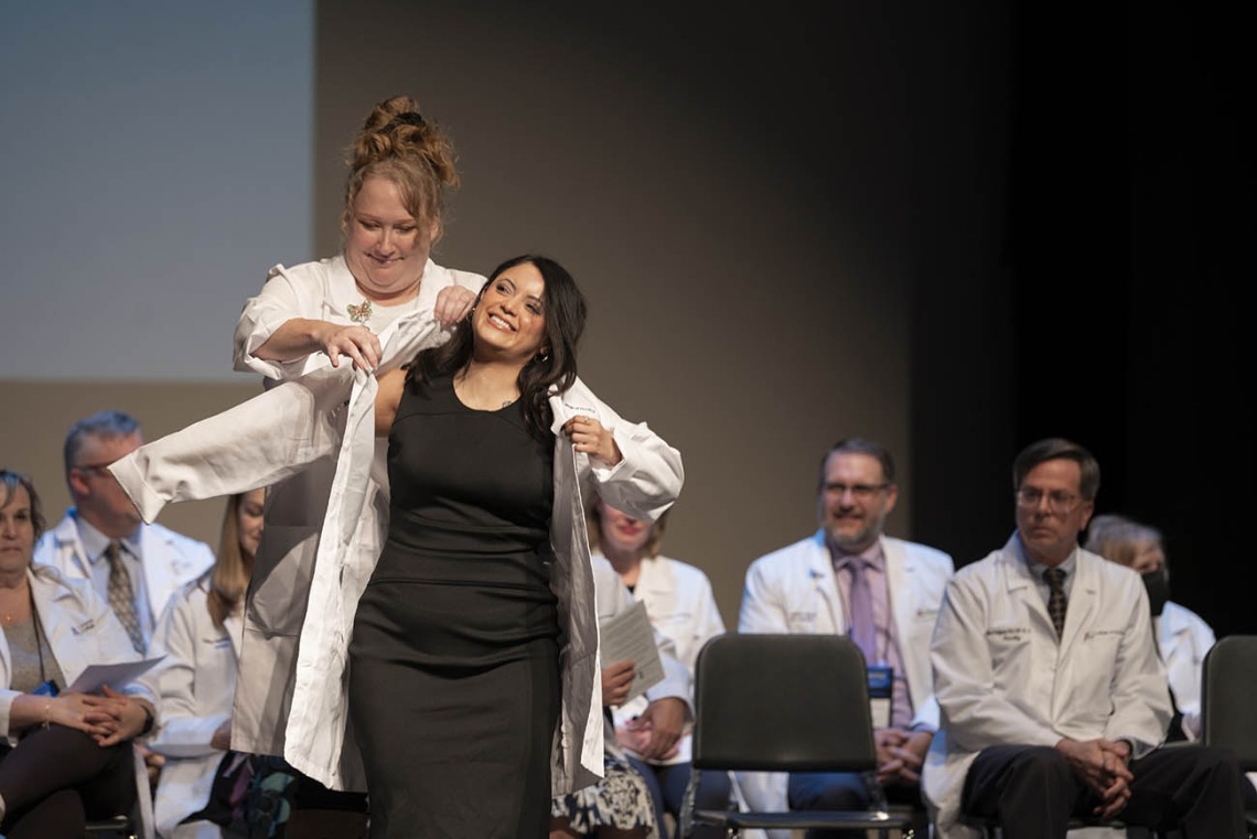 Professor Jennifer Hunter in the University of Arizona College of Nursing, helps Xitlali Arias-Ortiz into her coat at the college’s white coat ceremony.