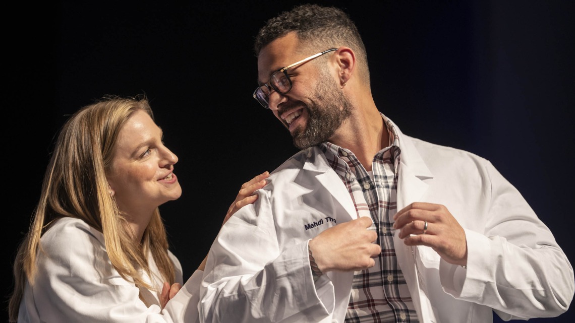 Dr. Lindsay Bouchard congratulates Mehdi Thomas after presenting him with his white coat at the UArizona College of Nursing white coat ceremony.