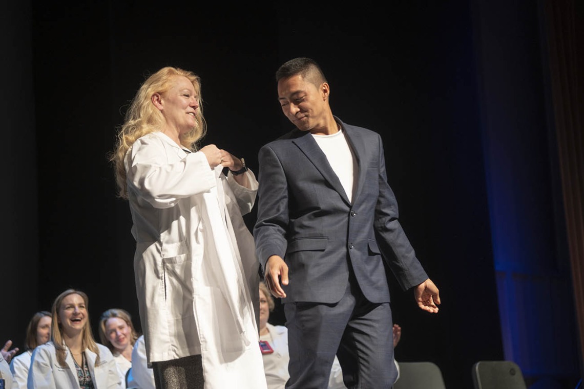Professor Kristie Hoch presents Sebastian Maderazo with his coat during the College of Nursing’s Doctor of Nursing Practice white coat ceremony.