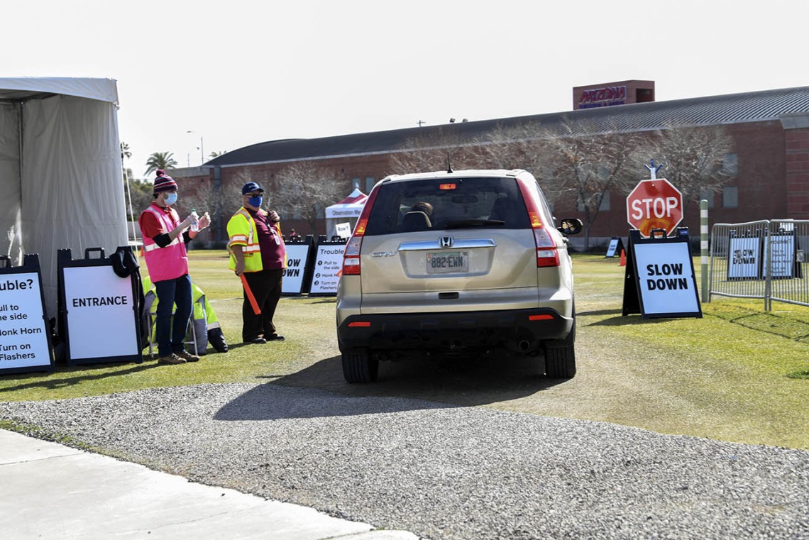 Brandon Goldstein, left, and Mike Wallace greet and direct drivers in the post-vaccine observation parking lot.
