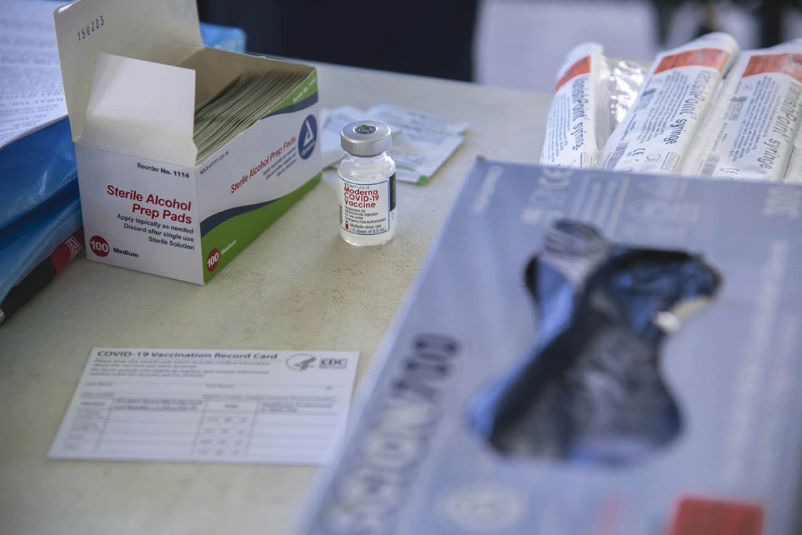 A table is stocked with the essentials: alcohol prep pads, needles, a vaccine card, gloves and Moderna’s COVID-19 vaccine.