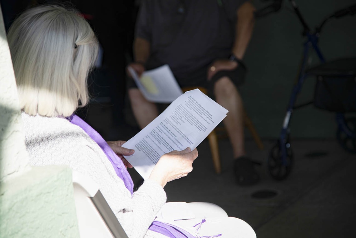 A resident from El Mirage Senior Village reads information about the COVID-19 vaccine as she waits to receive the first dose.