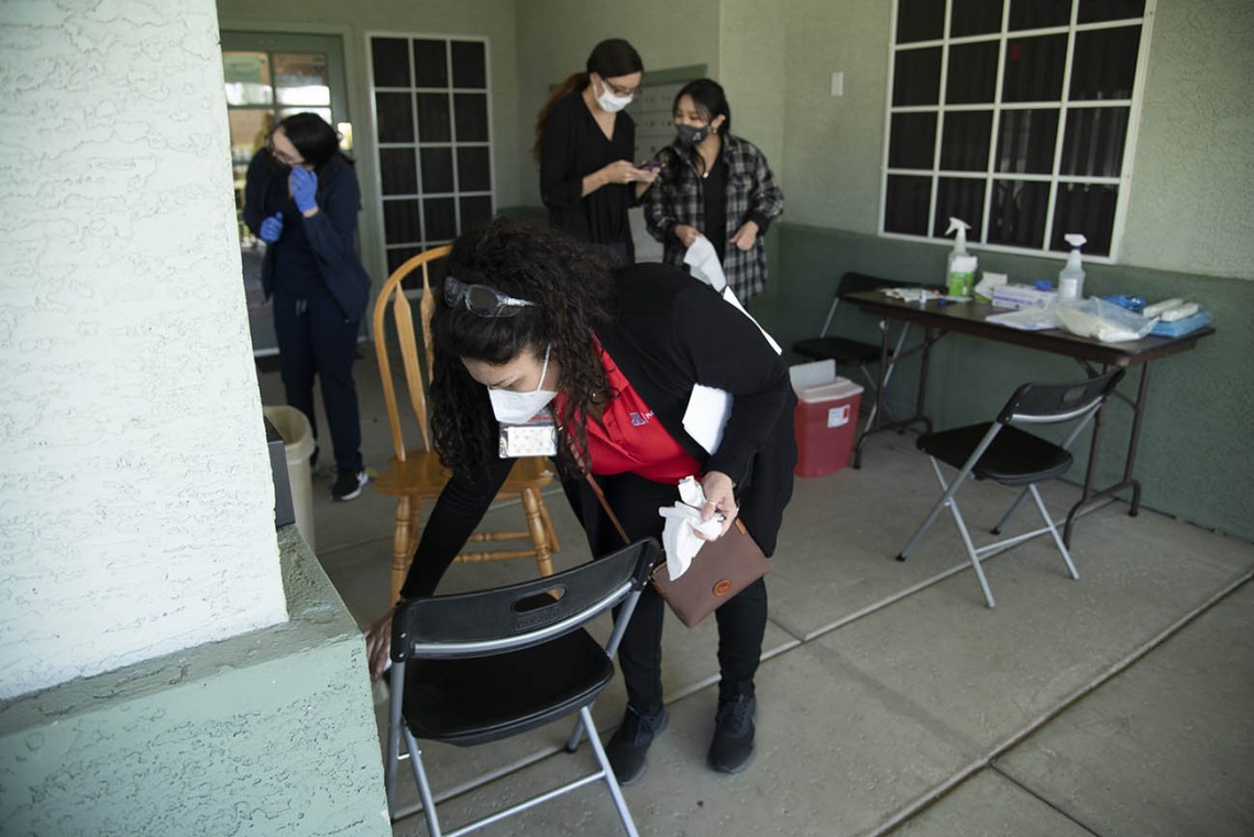 Maria Jaime, health educator from the College of Public Health in Phoenix, sanitizes a chair before the next patient sits down to receive the COVID-19 vaccine.
