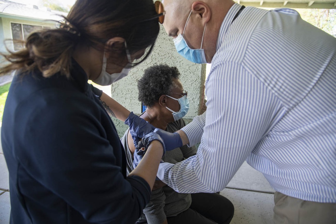 First-year College of Medicine – Phoenix student Bernice Alcanzo gives a COVID-19 vaccine to Alice Scott, resident service coordinator at El Mirage Senior Village, as Dr. Jim Lindgren assists.
