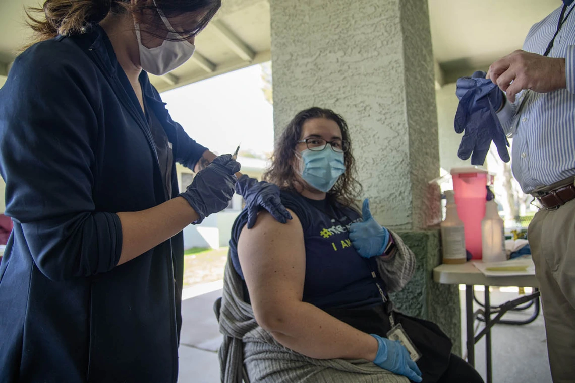 Shae Corea, a health care navigator for El Mirage Senior Village, gives a thumbs up before she receives the COVID-19 vaccine.