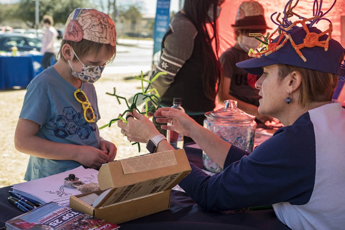 Jonathan Murphy listens to Helena Morrison, PhD, an associate professor at the University of Arizona College of Nursing, teach him about brain cells during the recent Family SciFest at Children's Museum Tucson. Murphy got to build brain cells out of pipe cleaners and was given a brain cell coloring sheet and stickers.