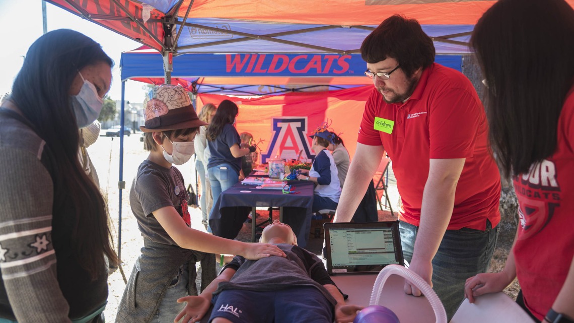 Insee Ekstrom checks to see if Hal, the young manikin, is breathing at the Arizona Simulation Technology and Education Center (ASTEC) booth, where they taught CPR and airway skills during the recent Family SciFest at Children's Museum Tucson.