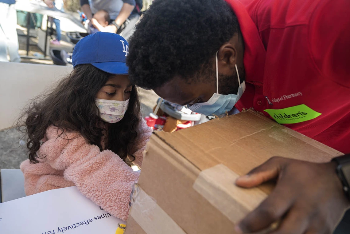 Vanessa Rendon places her hand in a box to see what germs are on her skin as University of Arizona R. Ken Coit College of Pharmacy student Anyang Ndobegang shines a black light on her hands during the recent Family SciFest at Children's Museum Tucson.