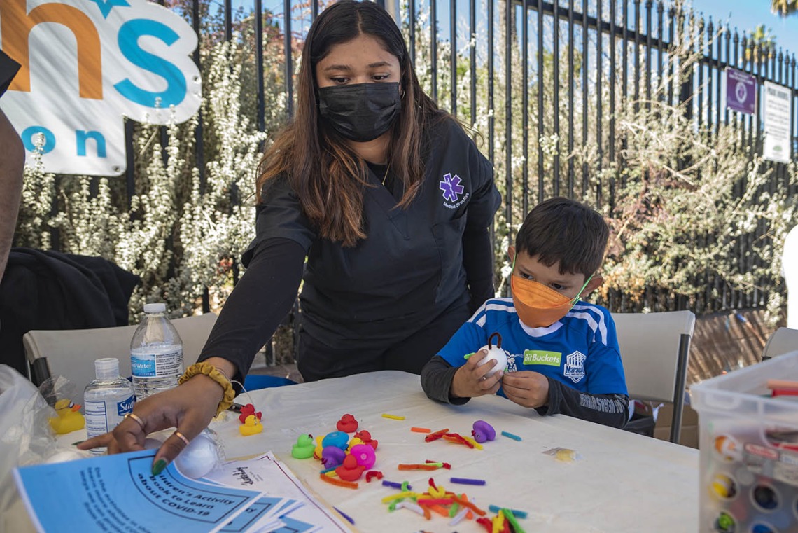 Medical Directive student Sakshi Akki gets a coloring booklet for Jay Mendoza while he makes a model of a virus during the recent Family SciFest at Children's Museum Tucson.