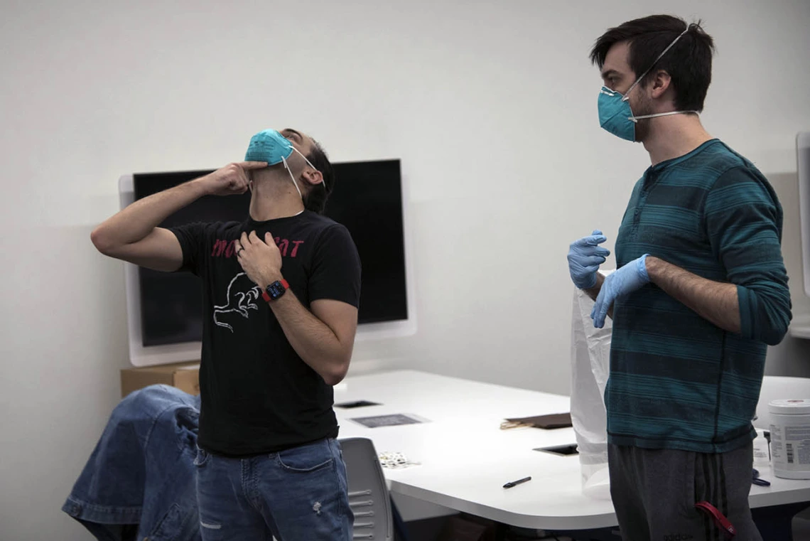 Second-year College of Medicine – Tucson student Alexandre Cavalcante adjusts his N95 mask as student-volunteer Billy Evans watches.