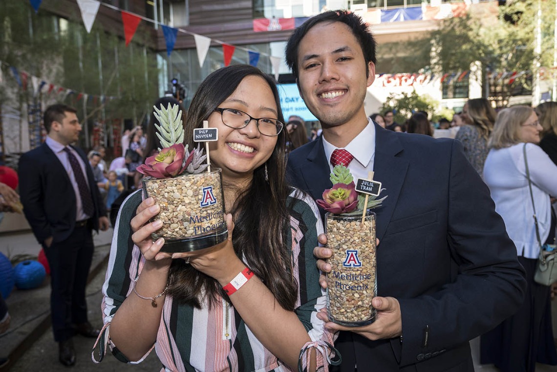 Julie Tran and Diep Nguyen pose for a photo holding each other’s succulent plants that contain their letters before the start of the College of Medicine-Phoenix Match Day 2022 event.