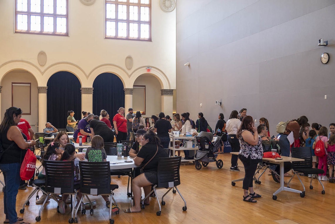 A big room filled with activity tables, girl scouts and adults all engaged with each other.