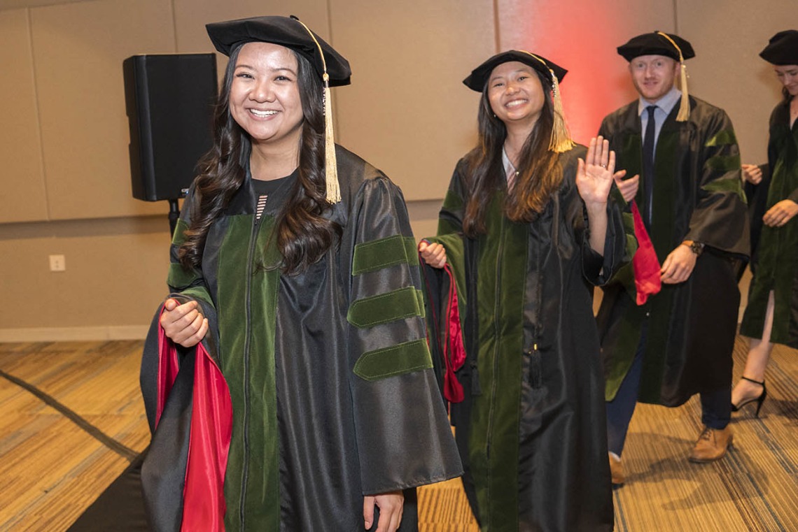 College of Medicine – Phoenix class of 2022 graduates (from front left) Amanda Tjitro, MD, Julie Tran, MD, and Blake Traube, MD, line up to be hooded during their commencement ceremony.