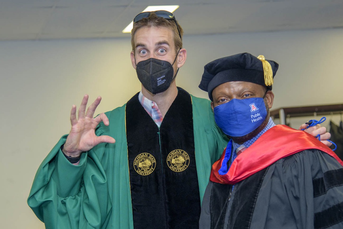 (From left) Marc Verhougstraete, PhD, assistant professor in the Department of Community, Environment and Policy, and John Ehiri, PhD, MPH, MSc, associate dean for academic affairs in the Mel and Enid Zuckerman College of Public Health, get ready for the college’s 2022 spring convocation ceremonies.