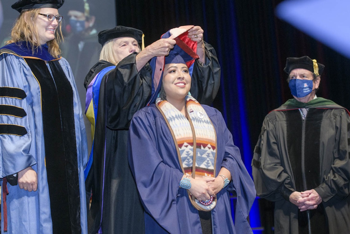 Carol Seanez, MPH, is hooded during the 2022 Mel and Enid Zuckerman College of Public Health spring convocation.