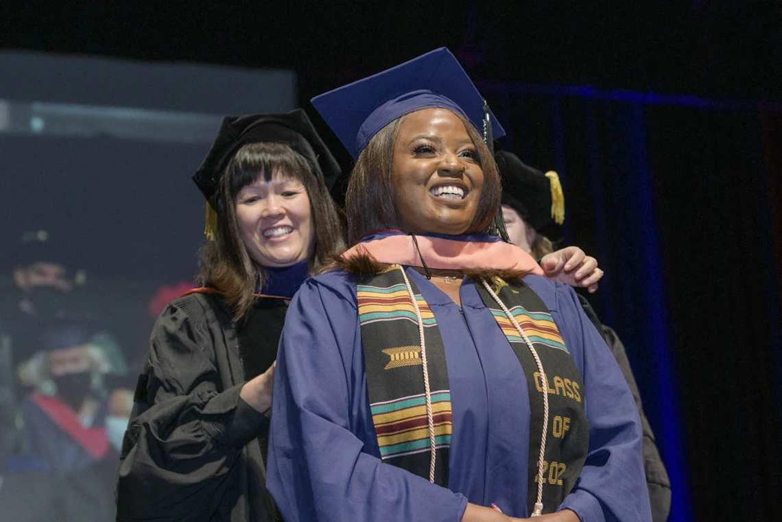 Master of Public Health student Eniola Idowu, MPH, is hooded during the 2022 Mel and Enid Zuckerman College of Public Health spring convocation.