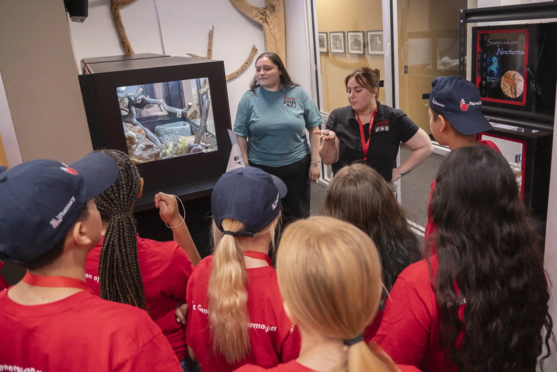 Two young women talk to a bunch of kids during a tour of the Arizona Poison and Drug Information Center.