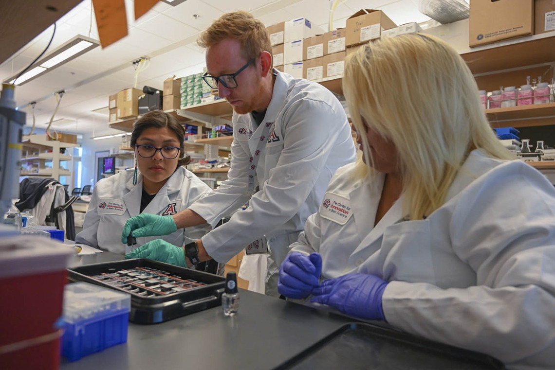 Diné College students Alyssa Joe (left) and Angel Leslie (right) work with graduate student David Bradford on an ALS-focused investigation at the UArizona Health Sciences Center for Innovation in Brain Science.