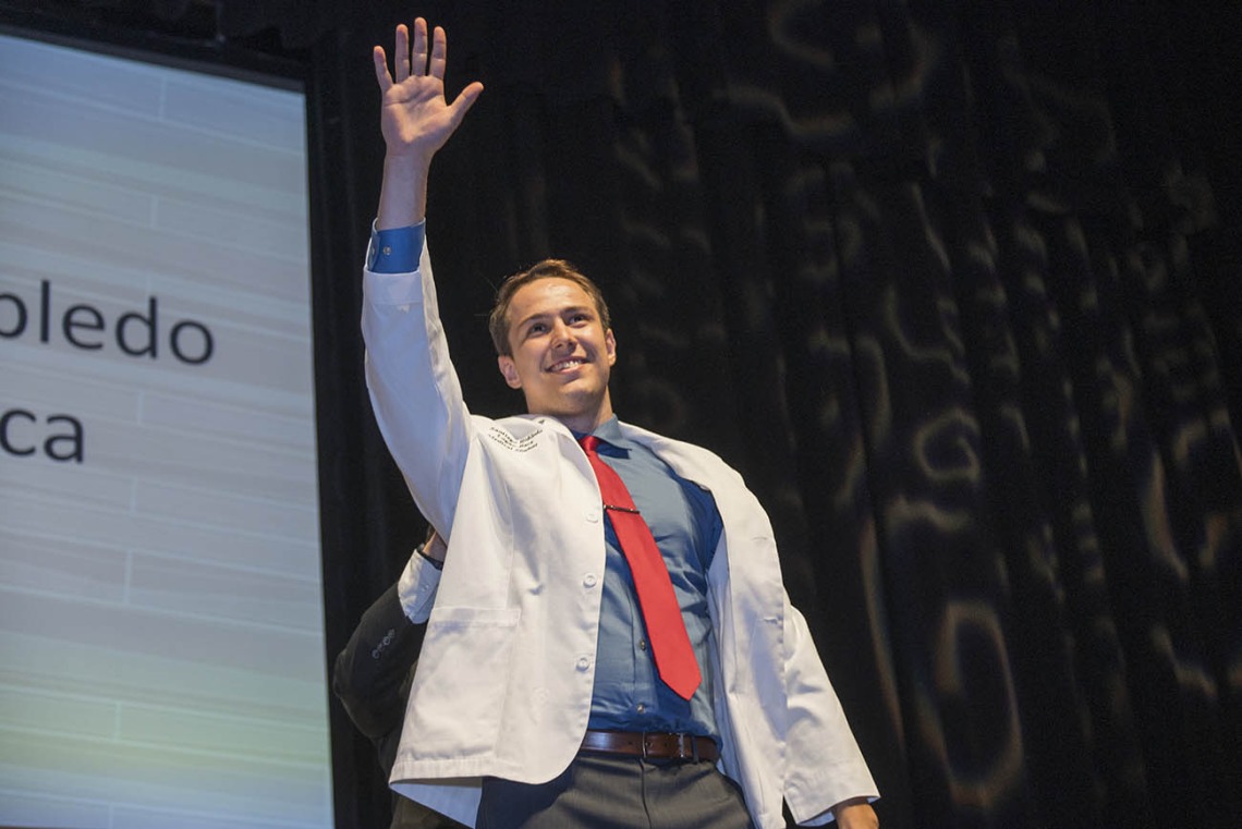 Santiago Robledo Logan-Baca waves to his family from the stage after receiving his white coat during the UArizona College of Medicine – Phoenix Class of 2026 white coat ceremony.