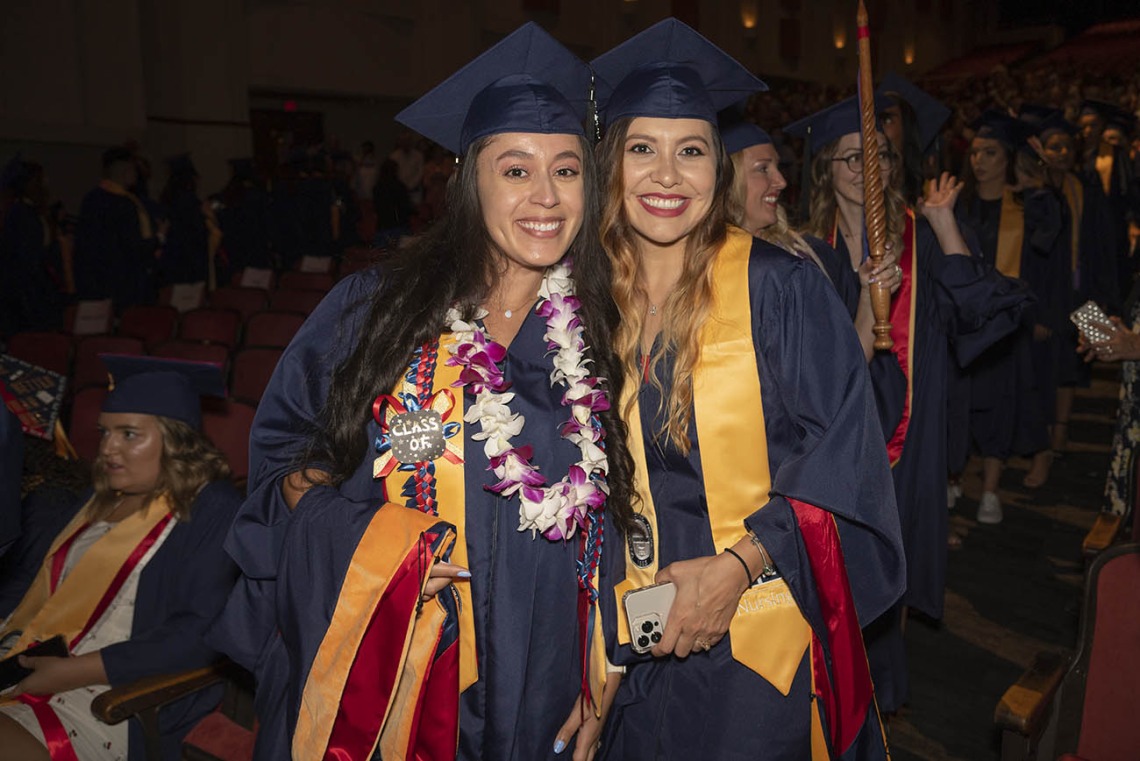 Yesenia Ordaz (left) and Raquel Mendoza, both Master of Science Entry to the Nursing Profession students, pause for a photo while going to their seats in Centennial Hall before the College of Nursing 2022 summer convocation.