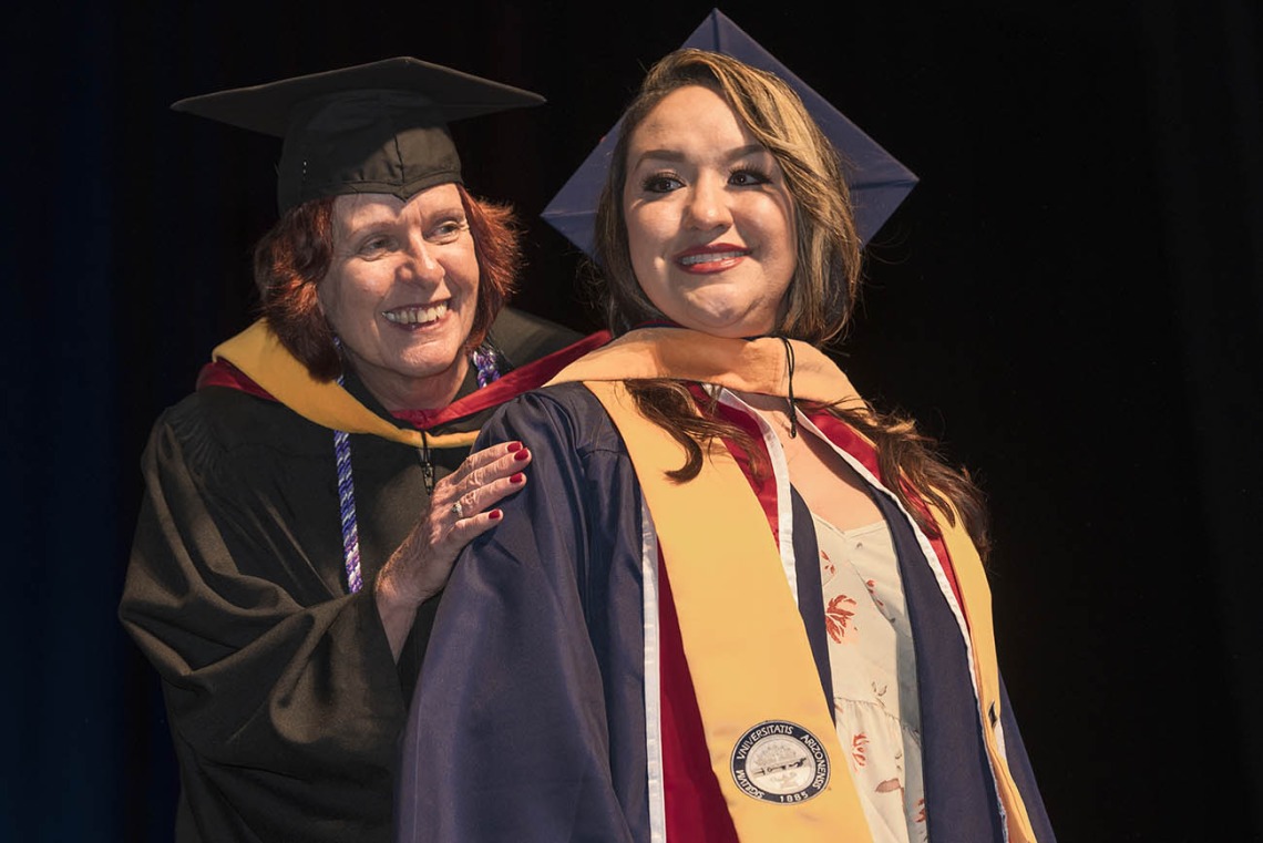 College of Nursing senior lecturer Kathleen Malkin, MSN, hoods Stephanie Figueroa, who earned a master’s degree in nursing clinical systems leadership, during the College of Nursing 2022 summer convocation.
