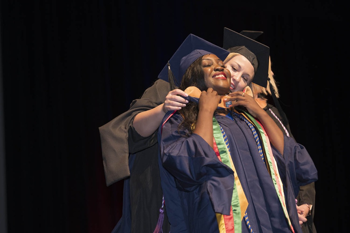 Master of Science in Nursing Entry to the Profession student Rosine Laure Bouguem is hooded by Carrie Van Bakel, MSN, during the College of Nursing’s 2022 summer convocation.