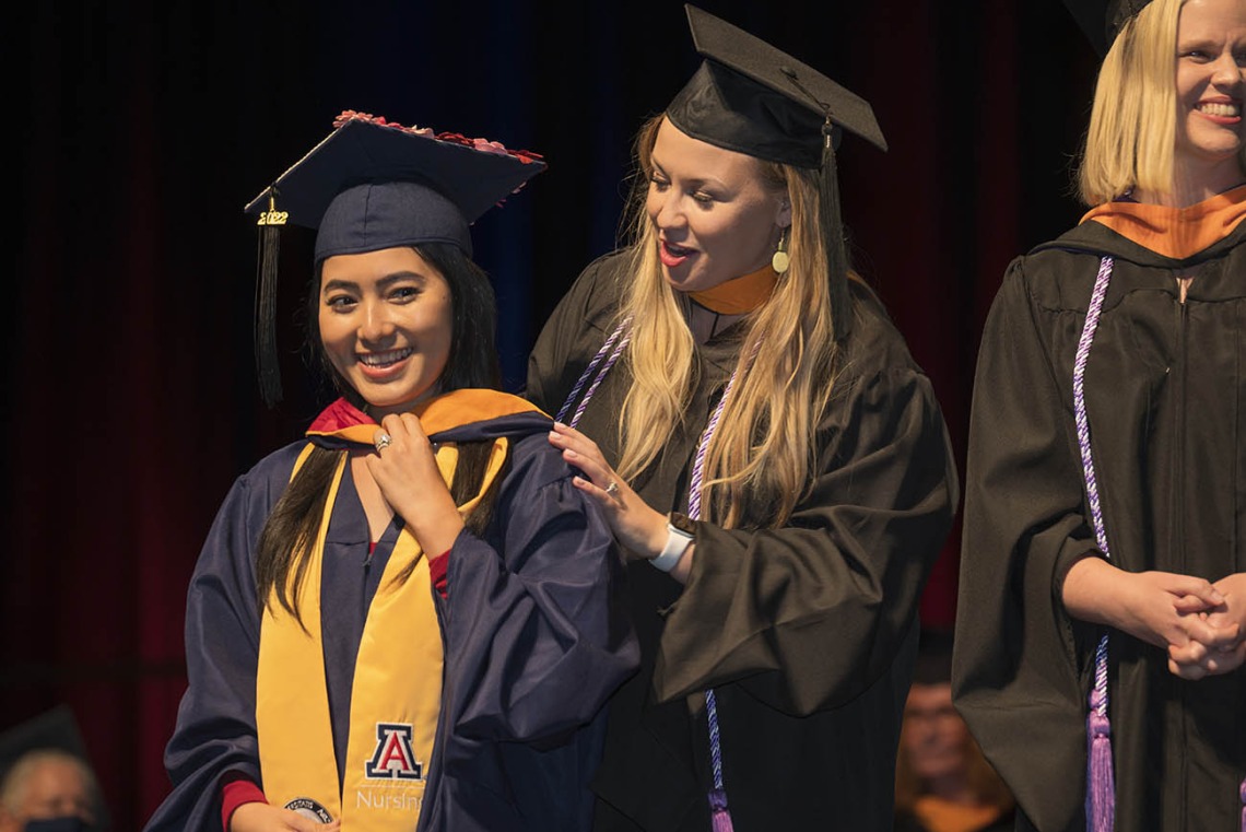 Master of Science in Nursing Entry to the Profession student Tun Pyai So Nef is hooded by Carrie Van Bakel, MSN, during the College of Nursing’s 2022 summer convocation.