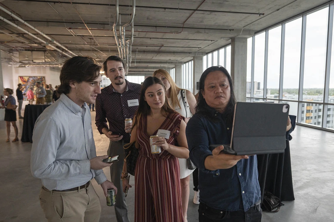 Artist Rembrandt Quiballo (right) demonstrates his augmented reality artwork, “It’s All in Your Head—Deconstructing the Brain Concussion” that he created based on research done by Theresa Currier Thomas, PhD, an associate professor in the College of Medicine – Phoenix, during the Artist + Researcher VIP exhibition.