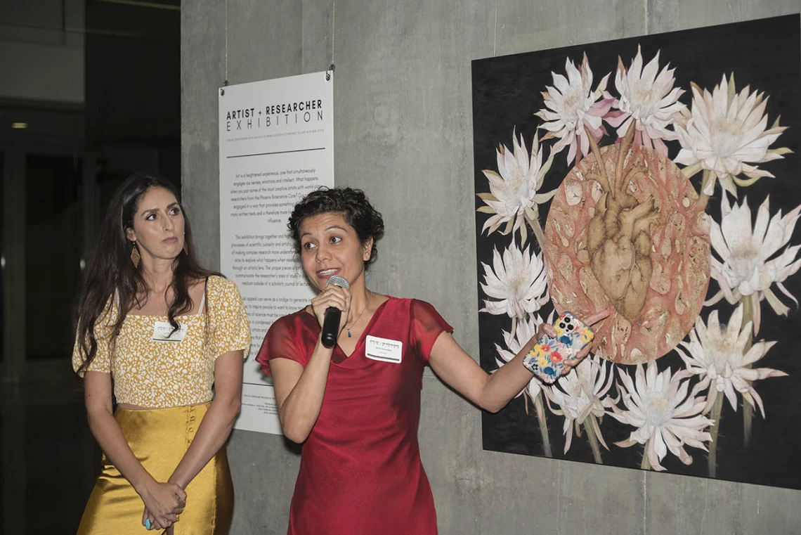 (From left) Artist Alexandra Bowers listens as Shirin Doroudgar, PhD, an assistant professor in the College of Medicine – Phoenix, talks about collaborating on the piece, “Deciphering the Nature of Cardiokines” during the public opening of the Artist + Researcher exhibition inside the Health Sciences Education Building.