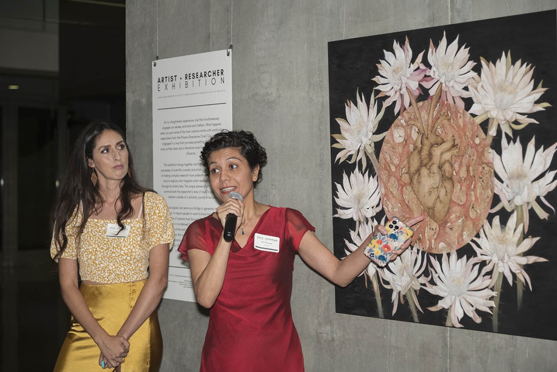 (From left) Artist Alexandra Bowers listens as Shirin Doroudgar, PhD, an assistant professor in the College of Medicine – Phoenix, talks about collaborating on the piece, “Deciphering the Nature of Cardiokines” during the public opening of the Artist + Researcher exhibition inside the Health Sciences Education Building.