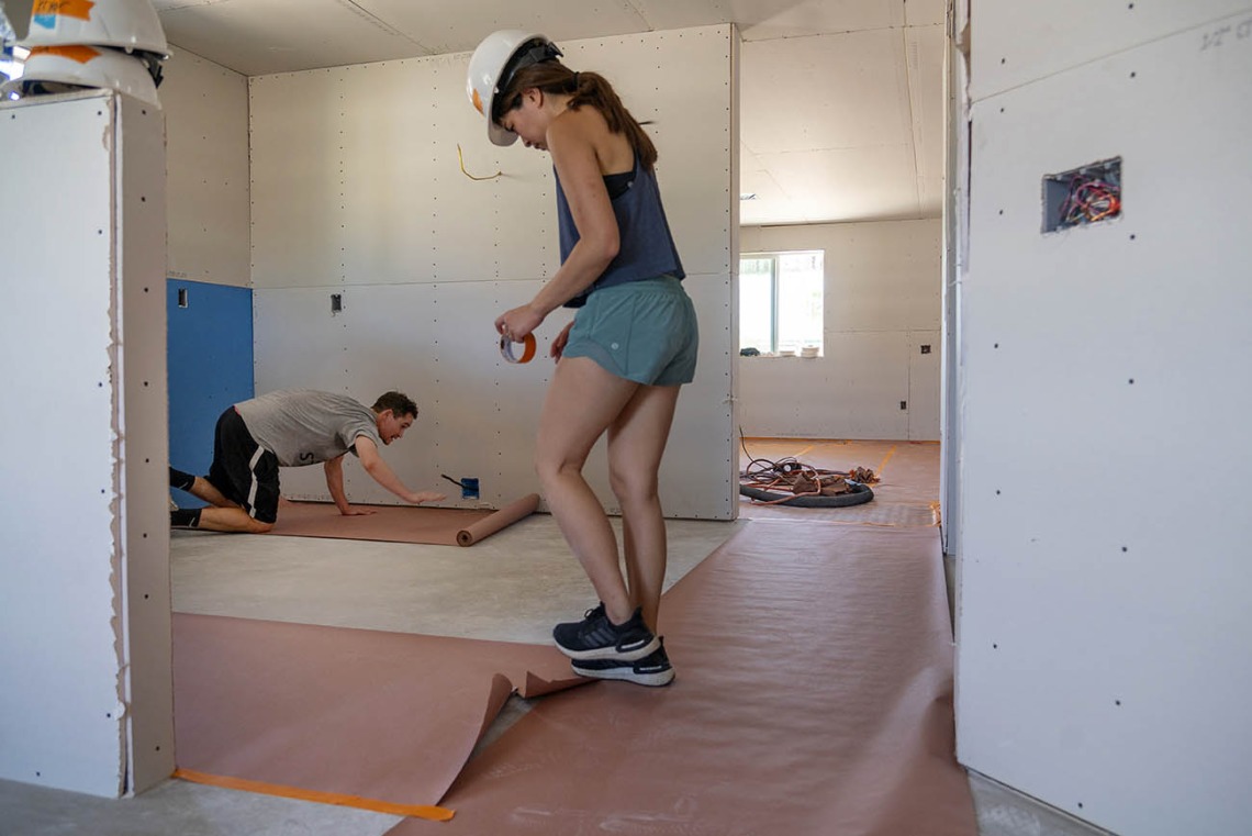Nolan Lassiter, DO, (in background) and Veronica Cheng, MD, both first-year emergency medicine residents at Banner – University Medical Center Tucson, cover the floor of a new Habitat for Humanity Tucson home with protective paper during the EM Day of Service.