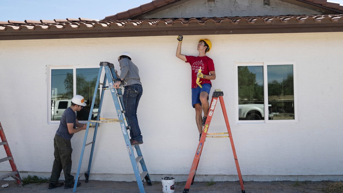 (From left) Volunteers Sawyer Thein, MD, Esteban Valle, MD, and Kevin Brandecker, MD, all first-year emergency medicine residents at Banner – University Medical Center Tucson, paint the eaves and trim on a Habitat for Humanity Tucson house during the EM Day of Service in late September.