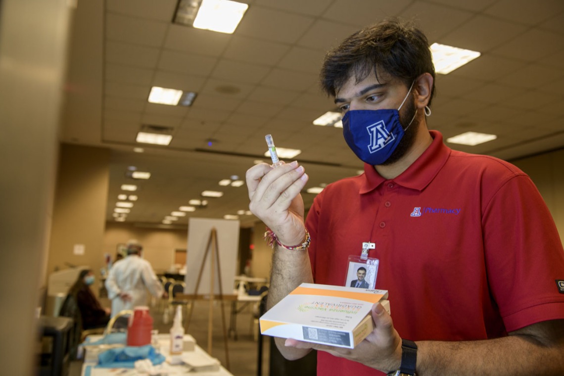 Kishan Hadvani, a PharmD student, prepares a flu vaccination for his next patient. He says he volunteered at the clinic to give back to the community.