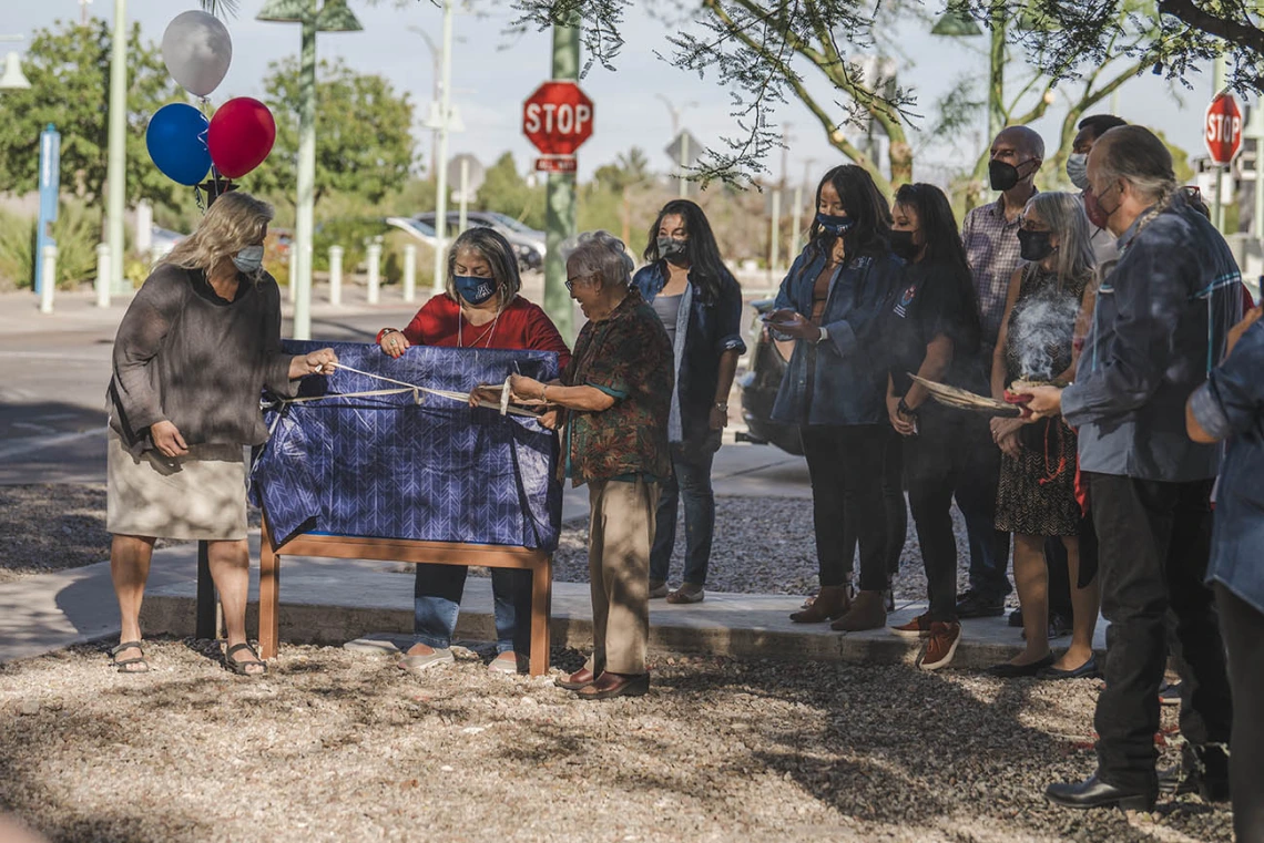 Ann Mathias, DO, interim chair, vice chair for clinical affairs, clinical assistant professor (left) and Jennie Joe, PhD, MPH, professor emerita, Family and Community Medicine, prepare to remove the covering over the new signage during the renaming ceremony for the Wassaja Carlos Montezuma Center for Native American Health.