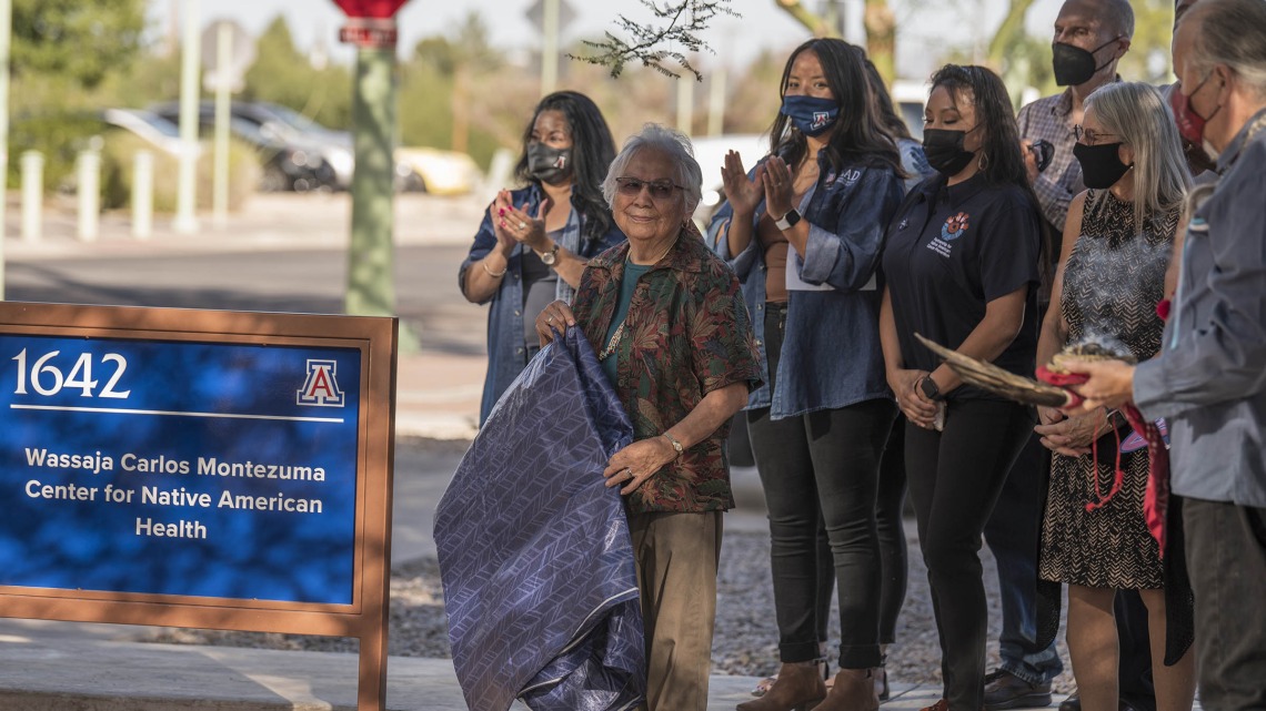 Jennie Joe, PhD, MPH, professor emerita, Family and Community Medicine, smiles after revealing the sign for the newly named Wassaja Carlos Montezuma Center for Native American Health in late October. 
