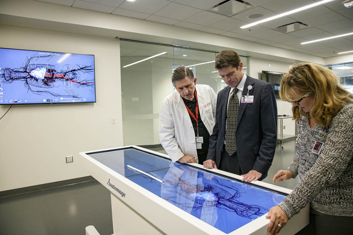 From left: Allan Hamilton, MD, FACS, executive director of ASTEC, Kevin Moynahan, MD, FACP, College of Medicine – Tucson deputy dean for education, and Deana Ann Smith, BS, BSN, RN, healthcare simulation educator, work on a life-size virtual dissection table. 