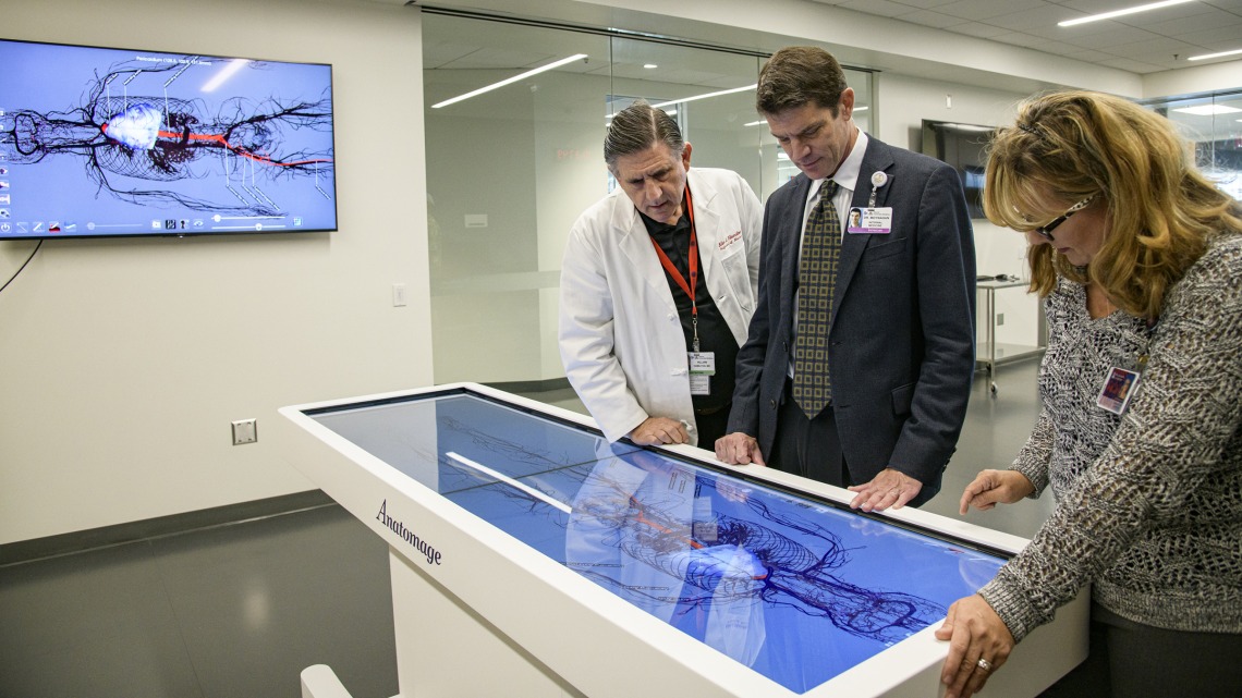 From left: Allan Hamilton, MD, executive director of ASTEC, Kevin Moynahan, MD, College of Medicine – Tucson deputy dean for education, and Deana Ann Smith, BS, BSN, RN, healthcare simulation educator, work on a life-size virtual dissection table. 