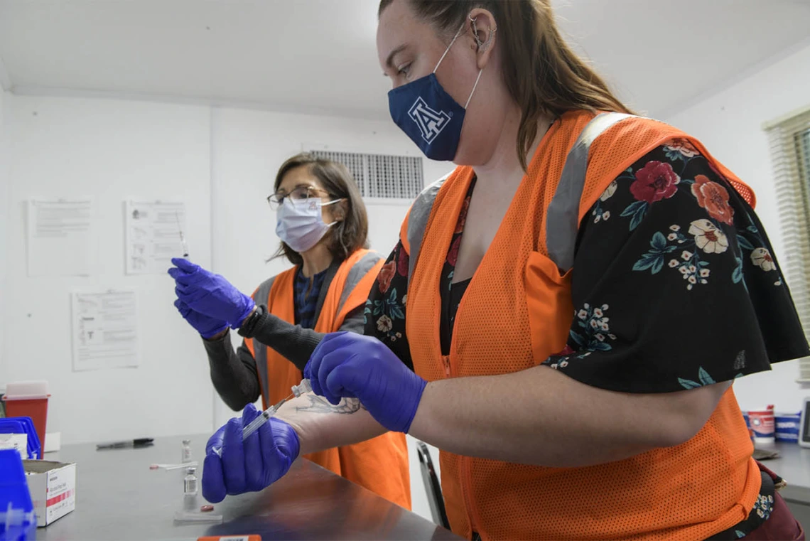 UArizona Campus Health registered pharmacist Elizabeth Preble (left), and fourth-year College of Pharmacy student Annie Hiller prepare to mix the Pfizer vaccine with saline.