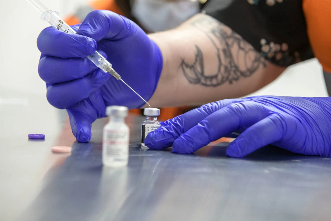 Hiller is shown mixing the contents of a Pfizer vaccine with a saline solution to get it ready for recipients. 